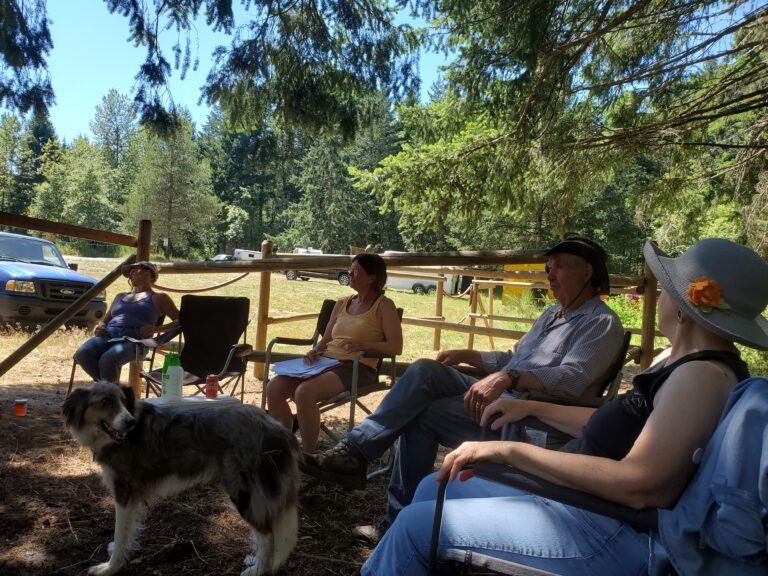 Chapter members relaxing beside the corrals with a dog at Spruston