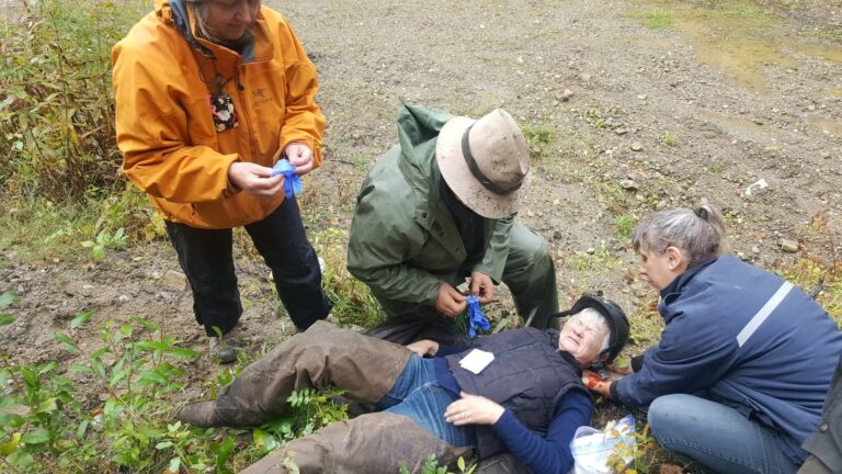 Chapter members practicing first aid on a person lying on the ground at a clinic