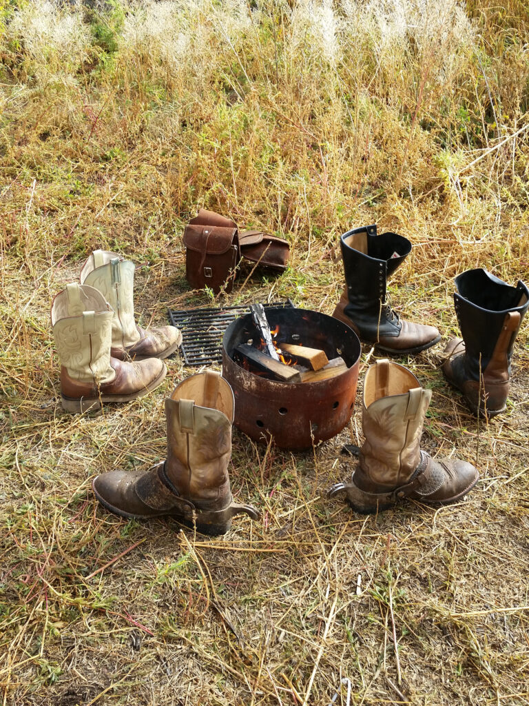Cowboy boots and saddlebags drying on the grass at camp