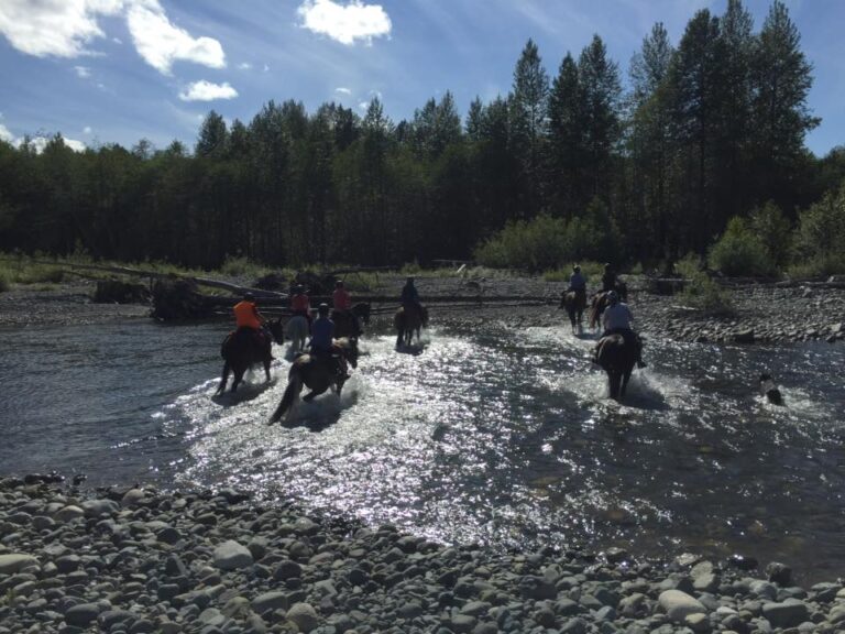 Riders crossing a shallow river on horseback