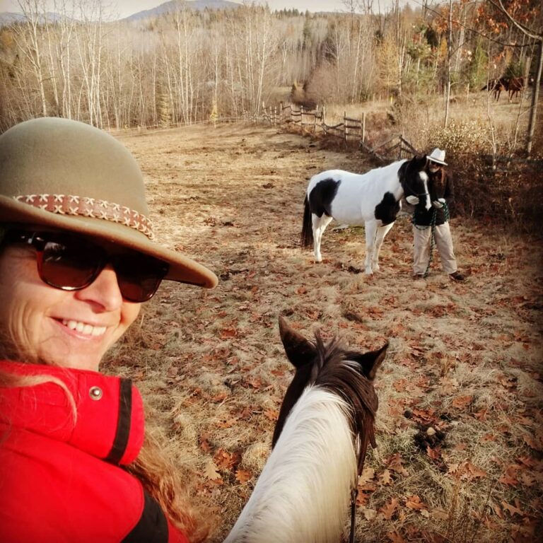 Rider taking a selfie on horseback with a paint horse on a forest trail