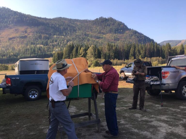 Chapter members demonstrating packing with a loaded horse beside trucks