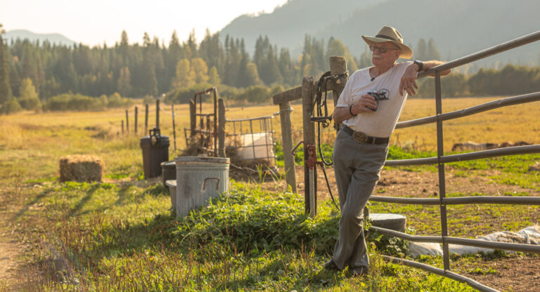 Chapter member beside a wooden corral at a mountain camp