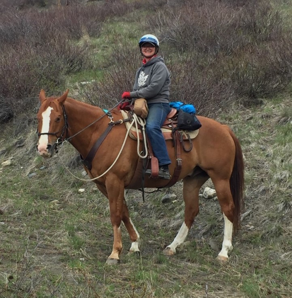 Rose Schroeder, BCHBC Provincial Secretary, on horseback on a hillside trail