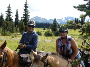 Two smiling riders in helmets on horseback on Belle Mountain