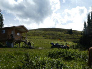 Cabin and alpine meadow on Belle Mountain under a cloudy sky