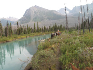 Riders beside a turquoise river in Mount Robson Provincial Park