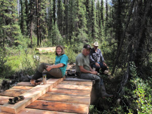 Volunteers resting beside newly built trail boardwalk sections