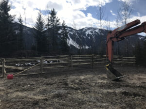Excavator building corrals at the Moose River staging area below snowy peaks