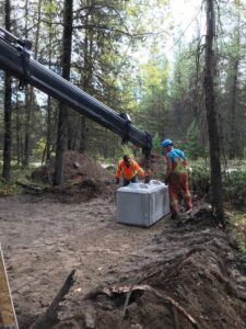 Crane truck placing concrete blocks for a manure bin at Trapping Creek camp