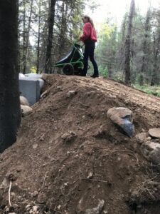 Volunteer with a wheelbarrow beside the new manure bin at Trapping Creek