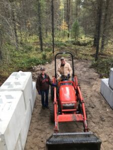 Volunteers with a small tractor at the new concrete manure bin at Trapping Creek